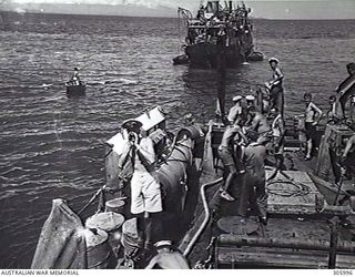 COLLINGWOOD BAY, NEW GUINEA. THE CORVETTE HMAS BROOME PREPARING TO TOW THE GROUNDED MERCHANT VESSEL COORABIE OFF A SHOAL. A TOWING HAWSER HAS BEEN PASSED BY BOAT TO THE STRANDED SHIP AND IS BEING ..