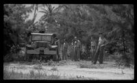 [Servicemen and military vehicle by dirt road]