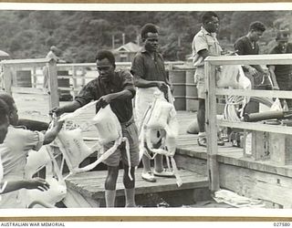 CLIFTON GARDENS, SYDNEY, AUSTRALIA. 1942-12. NATIVES OF THE PACIFIC ISLANDS SERVING WITH 1 AUSTRALIAN WATER TRANSPORT GROUP, SMALL SHIPS, ROYAL AUSTRALIAN ENGINEERS, LOADING SHIPS STORES ON TO ONE ..