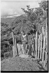 Young girl wearing shell valuables stands by a fence