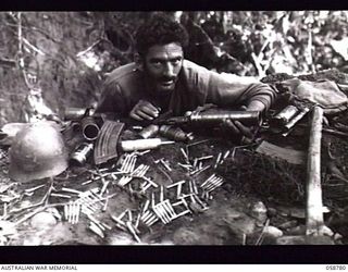 DUMPU, NEW GUINEA. 1943-10-07. WX11366 CORPORAL J. F. FOWLER OF THE 2/2ND AUSTRALIAN INDEPENDENT COMPANY WITH EQUIPMENT AND AMMUNITION LEFT BEHIND BY THE JAPANESE