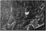 Pig festival, uprooting cordyline ritual, Tsembaga: man prepares to butcher meat from female pig sacrified to spirits of high ground, children watch