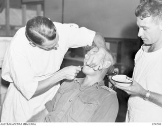 LAE, NEW GUINEA. 1944-11-09. NX102479 CAPTAIN R.W. HALLIDAY, DENTAL OFFICER, 112TH CONVALESCENT DEPOT (1) EXAMINING THE TEETH OF NX114729 LIEUTENANT J.N.G. MCDONAGH, 112TH CONVALESCENT DEPOT (2) ..