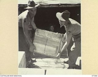 LAE, NEW GUINEA. 1944-03-29. Q37041 PRIVATE F. A. GOTTKE (LEFT), WITH N190091 PRIVATE D. C. GARDEN (RIGHT), LOAD TEA ON A TRUCK FOR ISSUE TO DETAIL ISSUE DEPOTS FROM THE 39TH SUPPLY DEPOT COMPANY