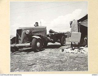 CAPE WOM, WEWAK AREA, NEW GUINEA. 1945-08-30. CRAFTSMAN R.F. GRIFFITHS, 2/4 ARMOURED REGIMENT WORKSHOP, CORPS OF AUSTRALIAN ELECTRICAL AND MECHANICAL ENGINEERS, SEATED AT WHEEL OF JAPANESE TRUCK