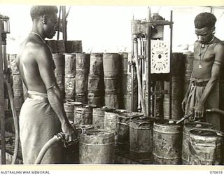 PORT MORESBY, PAPUA, 1944-02-25. NATIVES FILL 4-GALLON DRUMS AT THE CAN FILLING PLANT OF THE 1ST PETROLEUM STORAGE COMPANY