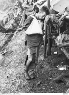 FINISTERRE RANGES, NEW GUINEA. 1944-01-23. QX53106 PRIVATE A.R. BIRCH, A WOUNDED MEMBER OF THE 2/9TH INFANTRY BATTALION WAITING FOR EVACUATION DURING THE BATTLE FOR SHAGGY RIDGE