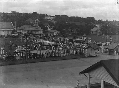 [A large crowd gathered along a main road in Tahiti]
