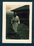 Don Honeysett dressed in a robe standing in front of a house, New Guinea, c1929 to 1932