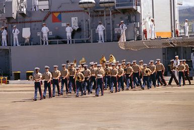 The Fleet Marine Force Pacific Band participates in the designation and departure ceremony for the Unknown Serviceman of the Vietnam Era. Crew members line the rail of the USS BREWTON (FF 1086) in the background. The frigate will transport the Unknown to Naval Air Station Alameda, California. From Alameda he will be taken to Travis Air Force Base for the flight to Washington, District of Columbia