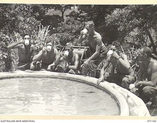 EVAPIA RIVER, NEW GUINEA, 1944-03-15. MEN OF THE 2/4TH FIELD COMPANY, ROYAL AUSTRALIAN ENGINEERS, WORKING ON THE ROAD TO KESAWAI, DIP INTO THE CANVAS WATER TANK FOR A REFRESHER