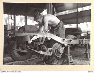 PALMALMAL PLANTATION, JACQUINOT BAY, NEW BRITAIN, 1945-06-06. CRAFTSMAN R. CRESSWELL, WELDER, 1 INFANTRY TROOPS WORKSHOP PREPARING AN OLD JEEP CHASSIS. HE IS WORKING ON THE 'WILLOW RUN' AN ASSEMBLY ..