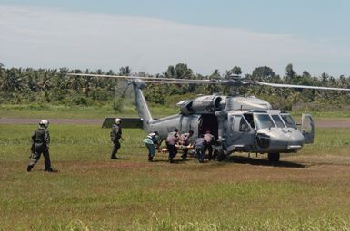 An Indonesian patient is carried to a US Navy (USN) MH-60S Seahawk helicopter, Helicopter Combat Support Squadron 5 (HC-5), Andersen Air Force Base (AFB), Guam, for medical evacuation from Nias Airport to the Military Sealift Command (MSC) hospital ship USNS MERCY (T-AH-19) off shore. At the request of the government of Indonesia, the MERCY and the MSC Combat Stores Ship USNS NIAGARA FALLS (T-AFS 3) [not shown] are on station off the coast of Nias, providing assistance in the wake of the devastating earthquake that struck the island March 28, 2005