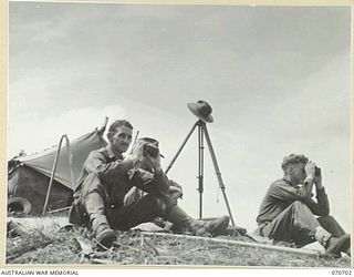 RAMU VALLEY, NEW GUINEA, 1944-02-29. THE OBSERVATION POST OFFICER OF THE 12TH BATTERY, 4TH FIELD REGIMENT, VX111264 CAPTAIN C.N. MCLEAN ( ), WATCHING A REGISTRATION SHOOT AST KESAWAI. IDENTIFIED ..