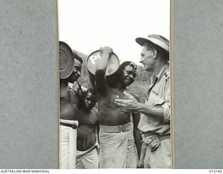 1943-06-28. NEW GUINEA. WAU-MUBO AREA. NATIVE CARRIERS LEAVE FOR FORWARD AREAS. ON ONE OF THE TRACKS THEY RECEIVE INSTRUCTIONS FROM LIEUT K. ALLEN, OF INVERELL, N.S.W. (NEGATIVE BY G. SHORT)