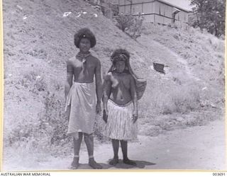 PORT MORESBY - PAPUAN "BOY" AND "MARY". IN STRING BAG, SUSPENDED FROM FOREHEAD, THE WOMEN HAD ABOUT 1 1/2 CWT. OF GOODS. LATER, THE "BOY" THREW A 50 LB BAG OF SUGAR ON TOP OF THAT LOT. RAAF SURVEY ..