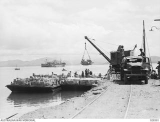 PORT MORESBY, PAPUA. 1942-09. UNLOADING SUPPLIES AT THE WHARF, PORT MORESBY. AS THERE IS ONLY ONE WHARF AT THIS PORT, SUPPLIES ARE UNLOADED FROM THE FREIGHTERS ON TO BARGES, WHICH ARE THEN ..