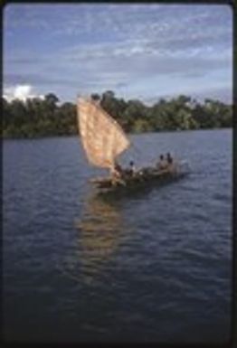 Canoe with sail up, near a small island