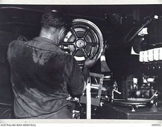 RABAUL, NEW BRITAIN, 1946-03-30. AN OPERATOR INSIDE A PROJECTION TRUCK PREPARING A FILM FOR SHOWING BY MOBILE CINEMA HQ UNIT NO 149, AUSTRALIAN ARMY AMENITIES SERVICE. SIX OF THESE UNITS SERVICE ..