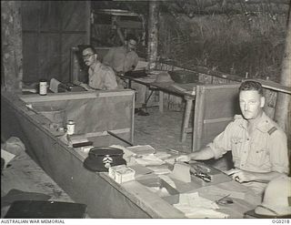 GOODENOUGH ISLAND, PAPUA. C. 1943-11. FLIGHT LIEUTENANT J. WATERS (FRONT), PILOT OFFICER S. HUTCHINSON (CENTRE) AND CORPORAL B. GRAHAM, RAAF PUBLIC RELATIONS PARTY AT WORK IN THEIR OFFICE AT ..