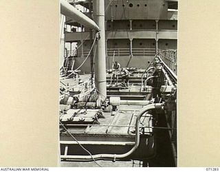 PORT MORESBY, PAPUA, 1944-03-21. THE OIL TANKS AND PUMPING PLANT ON THE FORE SECTION OF THE OIL TANKER EMPIRE SILVER. THE PERSON HOLDING THE DIP TAPE, USED IN CHECKING THE QUANTITY OF OIL ABOARD, ..