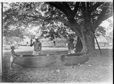 Two men playing wooden drums, watched by two young boys, Fiji, ca. 1920 / E.W. Searle