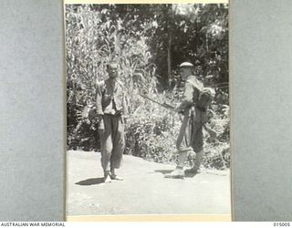 1943-06-15. NEW GUINEA. AUSTRALIAN INFANTRYMAN WITH JAP PRISONER, IN NEW GUINEA. (NEGATIVE BY G. SILK)