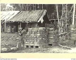 LAE, NEW GUINEA. 1944-03-29. VX101368 STAFF SERGEANT F. STUART-BOYLE, STACKING AMMUNITION AT THE RETURNED STORES AMMUNITION DEPOT, 103RD FIELD AMMUNITION DEPOT. THE BACKGROUND TO THE PHOTOGRAPH ..