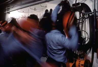 Members of a firefighting team rush to don protective gear during a drill aboard the amphibous assault ship USS GUAM (LPH 9)