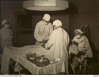 Lae, New Guinea. 1944-08-02. Major E. A. Hedberg (1) assisted by Sister H. Walker (2) and Corporal Henderson, Theatre Orderly (3,) performing an operation at 2/7th Australian General Hospital