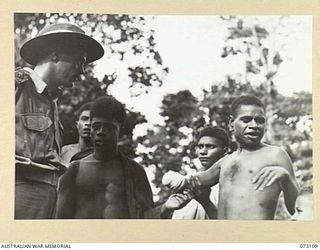 REMPI, NEW GUINEA. 1944-05-09. AN OFFICER FROM THE 35TH INFANTRY BATTALION (1), QUESTIONS NATIVES BESIDE THE ROAD TO ALEXISHAFEN. THE NATIVES HAVE EMERGED FROM THE JUNGLE IN RESPONSE TO A CALL MADE ..