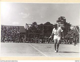 TOROKINA, BOUGAINVILLE. 1945-11-17. MR B.G. TONKIN, YMCA REPRESENTATIVE, 8 INFANTRY BATTALION (1) RETURNS A VOLLEY FROM BOMBARDIER R.H. STEPHEN, 2/11 FIELD REGIMENT, DURING AN EXHIBITION TENNIS ..