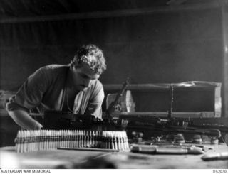 BOUGAINVILLE ISLAND, SOLOMON ISLANDS. 1945-01-17. 71220 LEADING AIRCRAFTMAN R. H. STUDMAN OF CANBERRA, ACT, SERVICING BROWNING .303 INCH MACHINE GUNS USED IN AUSTRALIAN BUILT BOOMERANG AIRCRAFT OF ..