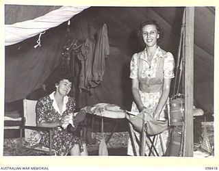 RABAUL, NEW BRITAIN. 1945-10-31. WARRANT OFFICER 2 G. GILLOT (1) AND CORPORAL D. MASSEY (2), SPRUCING UP AFTER COMING OFF DUTY. THEY ARE BOTH AUSTRALIAN ARMY MEDICAL WOMEN'S SERVICE PERSONNEL OF ..