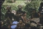 Mortuary ceremony: mourning women, skins blackened with ash, at exchange of banana leaf bundles
