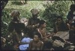 Mortuary ceremony: mourning women, skins blackened with ash, at exchange of banana leaf bundles