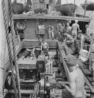 WIDE BAY, NEW BRITAIN. 1945-05-06. A WORKING PARTY FROM 11 INFANTRY BATTALION AT WORK ABOARD THE AK 82 (FORMERLY THE ALMA DOEPEL), 16 WATERCRAFT COMPANY, ROYAL AUSTRALIAN ENGINEERS, DISCHARGING A ..