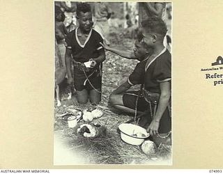 PORT MORESBY, PAPUA. 1944-08-05. MEMBERS OF THE ROYAL PAPUAN CONSTABULARY BAND ENJOYING A MEAL AFTER THEIR BAND RECITAL AND MARCHING DISPLAY AT MALARA VILLAGE FOR THE GENERAL OFFICER COMMANDING, ..