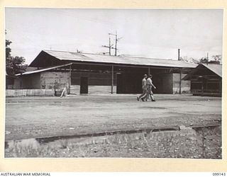 LAE, NEW GUINEA. 1945-11-20. THE FRONT VIEW OF THE ICEWORKS FORMERLY OPERATED BY BURNS PHILP. THE SMALL ADDITION AT THE LEFT OF THE MAIN BUILDING WAS MADE BY 615 UNITED STATES ENGINEERS. MEMBERS OF ..