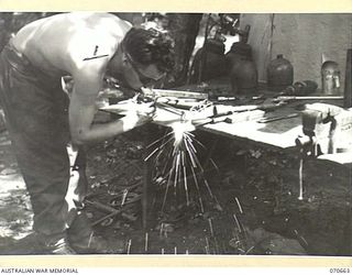 DALLMAN RIVER, NEW GUINEA, 1944-02-25. VX137732 CORPORAL R.A. GOODWILL, OF THE 231ST LIGHT AID DETACHMENT, USING AN OXYACETYLENE WELDING OUTFIT