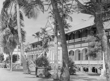 [View of building, a canon and many palm trees]