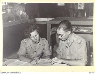 LAE, NEW GUINEA. 1945-05-15. LIEUTENANT E.J. MEIGHAN (1), AND WARRANT OFFICER 1 W.M.G. HOSKINS (2), CHECKING STOCK REPORTS. A FEW DAYS AFTER THEIR ARRIVAL FROM AUSTRALIA, AUSTRALIAN WOMEN'S ARMY ..