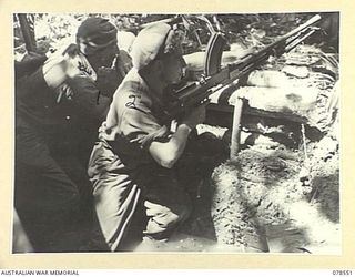 BOUGAINVILLE ISLAND, 1945-01-21. QX62583 PRIVATE G.S.J. PAYNE (1) AND SX33240 PRIVATE A.J. LEMM (2) IN THEIR WATER FILLED DUGOUT COVERING AN AREA WHERE JAPANESE RAIDERS COULD MOVE IN AGAIN AND ..