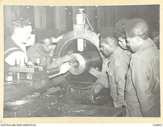 MARIBYRNONG, AUSTRALIA. 1942-10-12. A PARTY OF SIX NATIVE SOLDIERS FROM NEW GUINEA WERE SHOWN OVER THE MUNITION WORKS AND HERE ARE SEEN SOME OF THEM EXAMINING THE BORE OF AN ANTI-AIRCRAFT GUN