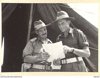 MISSION POINT, NEW GUINEA. 1945-10-24. CAPTAIN G.E. CORY, ADJUTANT AND MAJOR L.E. POWLING, ADMINISTRATIVE COMMANDER, 67 INFANTRY BATTALION (BRITISH COMMONWEALTH OCCUPATION FORCE (BCOF)), DISCUSSING ..