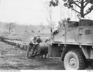 NADZAB, NEW GUINEA. 1944-07-21. TROOPS OF THE 39TH LINES OF COMMUNICATION SALVAGE SECTION, HEAQUARTERS, 8TH SALVAGE DEPOT, LOADING DRUMS OF USED AVIATION OIL ONTO A TRUCK FOR TRANSPORT BACK TO THE ..