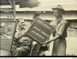 MADANG, NEW GUINEA. C. 1944-10. 129162 LEADING AIRCRAFTMAN S. J. CAMPBELL, HEATHCOTE, VIC, DELIVERS PROGRAMMES TO 435397 SERGEANT F. E. J. SHEPPARD, BRISBANE, QLD. SHEPPARD IS A FORMER ABC ..