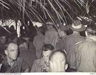 MALMAL VILLAGE, NEW BRITAIN. 1944-12-25. VX27 MAJOR GENERAL A. H. RAMSAY, CBE, DSO, ED, GENERAL OFFICER COMMANDING 5TH DIVISION (3) AND HIS SENIOR OFFICERS WALKING THROUGH THE MEN'S MESS DURING ..