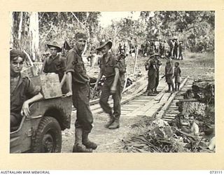 REMPI, NEW GUINEA. 1944-05-09. MEMBERS OF "A" COMPANY, 35TH INFANTRY BATTALION CROSS A BRIDGE OVER A STREAM NEAR REMPI DURING THE MOVEMENT OF SUPPLIES TO A FORWARD AREA. IDENTIFIED PERSONNEL ARE:- ..