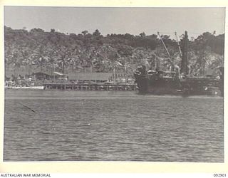 JACQUINOT BAY, NEW BRITAIN. 1945-06-10. THE LIBERTY SHIP OTTO MEYER EDGES INTO THE WHARF WHILE BERTHING AT HEADQUARTERS 5 DIVISION. ORDNANCE DUMPS ARE AT LEFT AMONG THE TREES